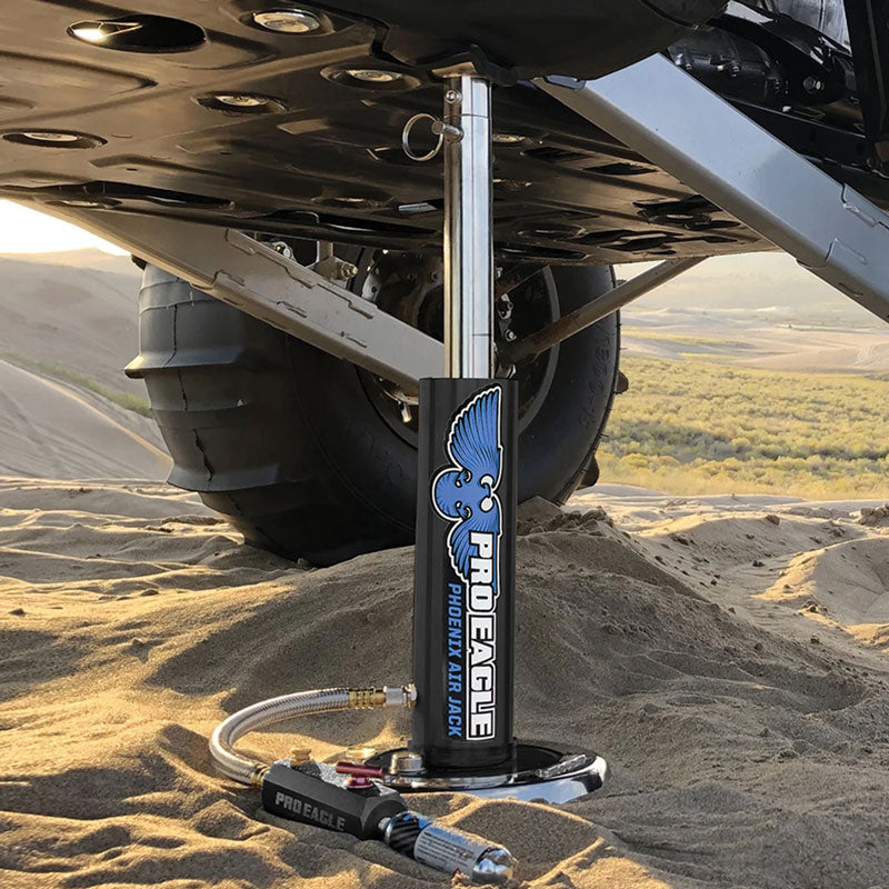 Pro Eagle CO2 air jack positioned under a vehicle on a sandy terrain, showcasing durability and utility.